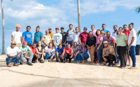 group photo a large team of biologists on a beach with palm trees in the background